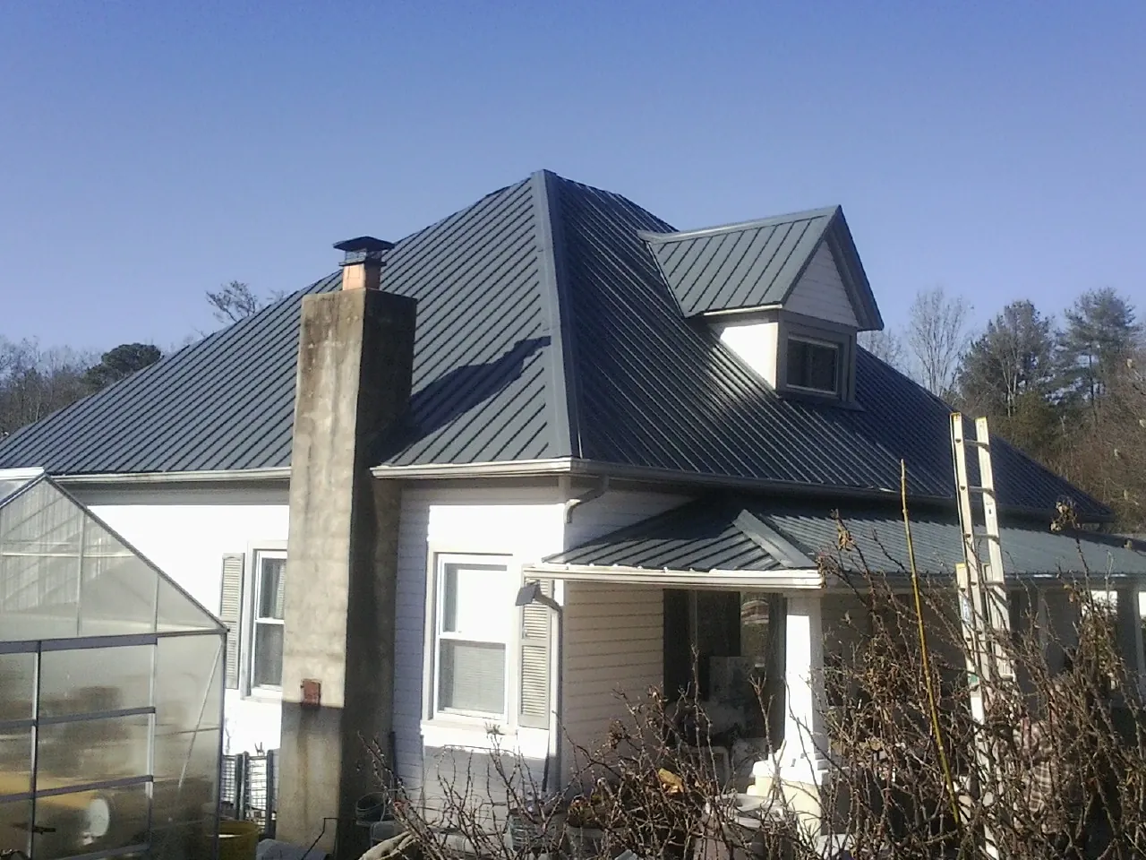 Dark blue standing seam metal roof on a white farmhouse with dormer — Slate & Tile Roof Repair by Roofing Brothers in Vineland