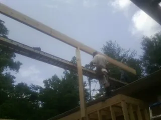 Carpenter setting a ridge beam over a new addition frame — Ice Dam Removal by Roofing Brothers in Vineland