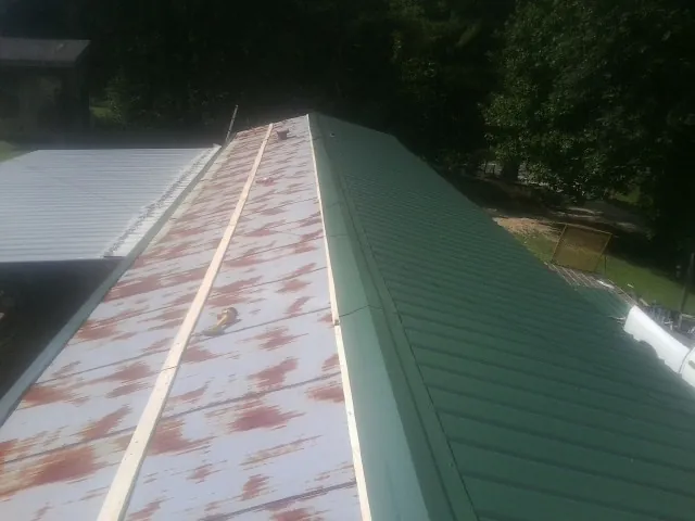 Old rusted panels beside newly installed green metal roofing — Wind Damage Roof Repair by Roofing Brothers in Vineland