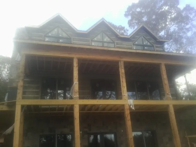 Dormers and porch framing on a large log home under construction — Roof Coating work by our crew in Vineland