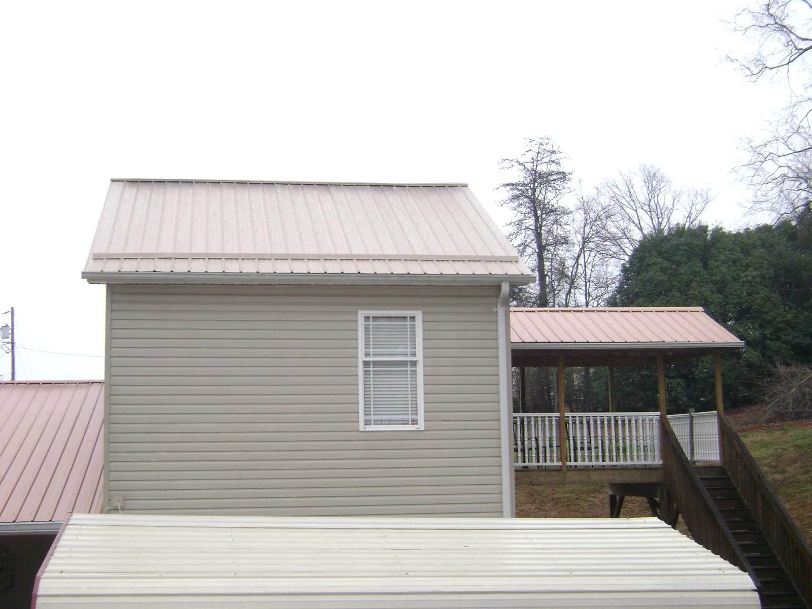 Tan metal roofs on a two story addition and attached porch, from a Roof Replacement job in Vineland