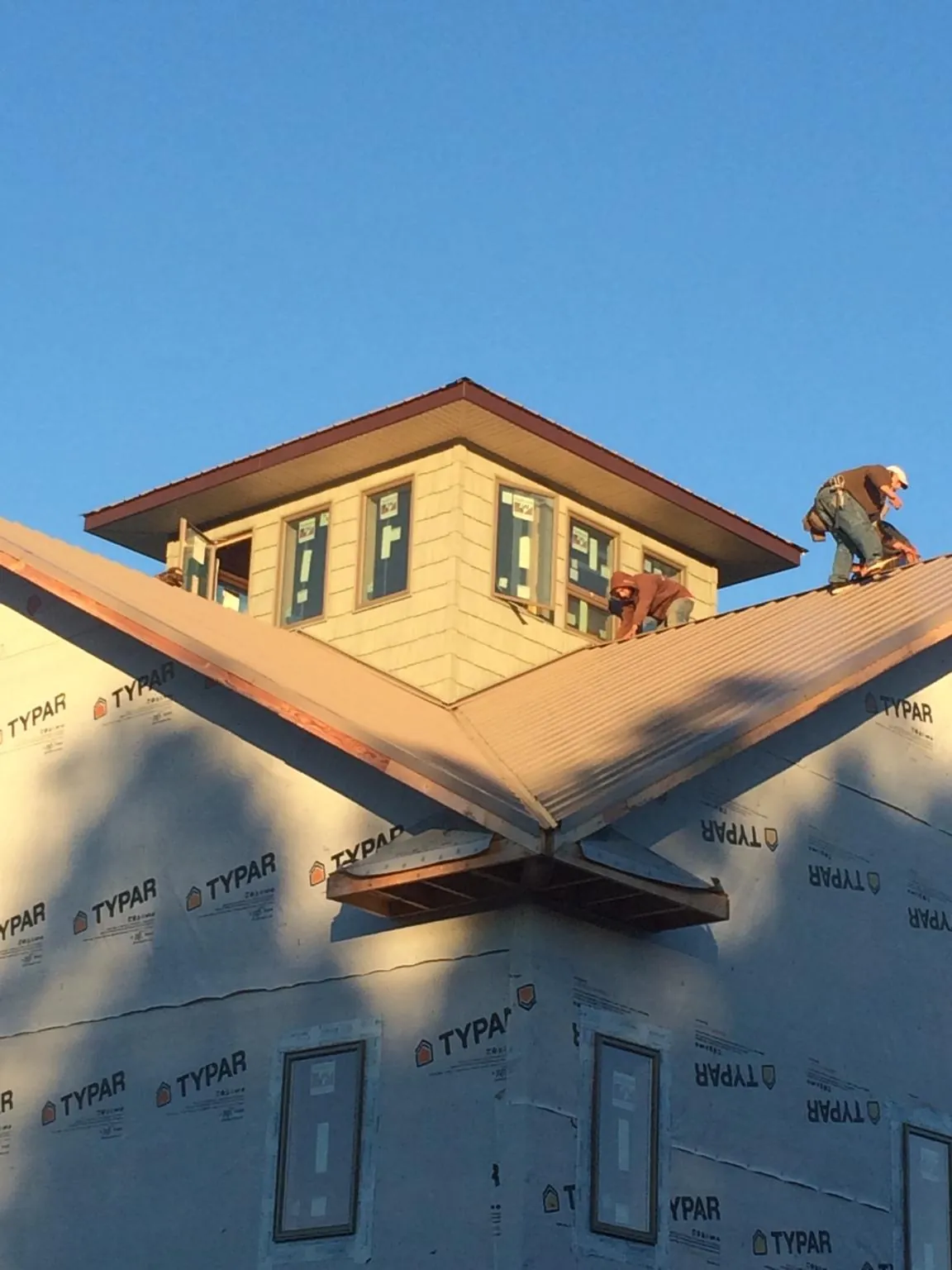 Roofers working around a rooftop cupola on a new metal roof at sunset — Roof Waterproofing in Vineland by Roofing Brothers